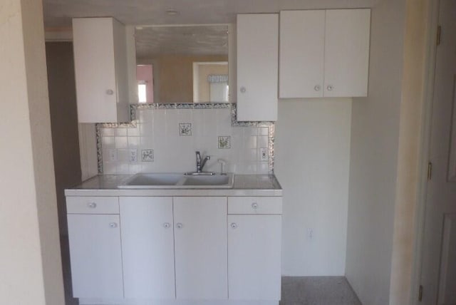 kitchen with a sink, backsplash, and white cabinetry