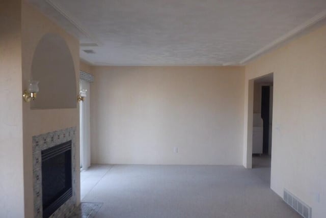 unfurnished living room featuring visible vents, light colored carpet, and a tile fireplace