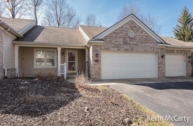 ranch-style house with a garage, brick siding, driveway, and a shingled roof