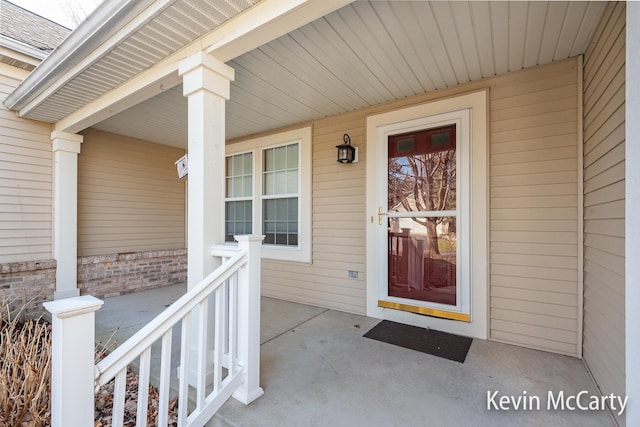 doorway to property featuring roof with shingles and a porch