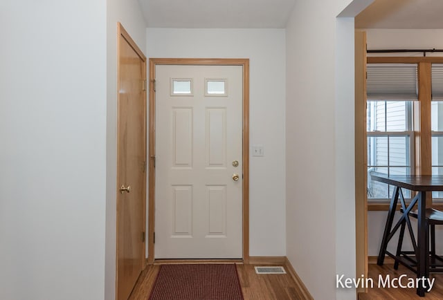 doorway to outside featuring visible vents, baseboards, and wood finished floors