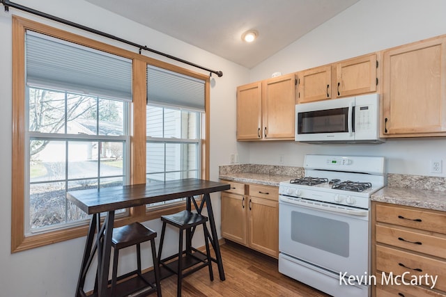 kitchen with white appliances, plenty of natural light, light brown cabinets, and lofted ceiling