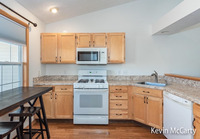 kitchen with light brown cabinets, white appliances, and a sink