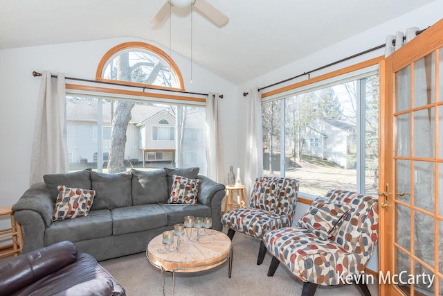 carpeted living area with a wealth of natural light, ceiling fan, and vaulted ceiling