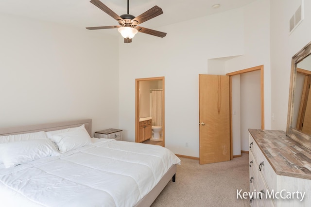 bedroom featuring visible vents, baseboards, ensuite bath, a high ceiling, and light colored carpet