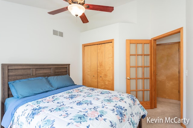 carpeted bedroom featuring lofted ceiling, visible vents, a closet, and ceiling fan