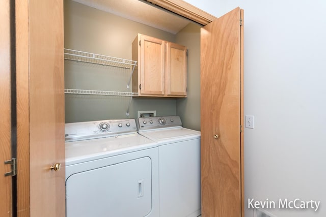 clothes washing area featuring cabinet space and washer and clothes dryer