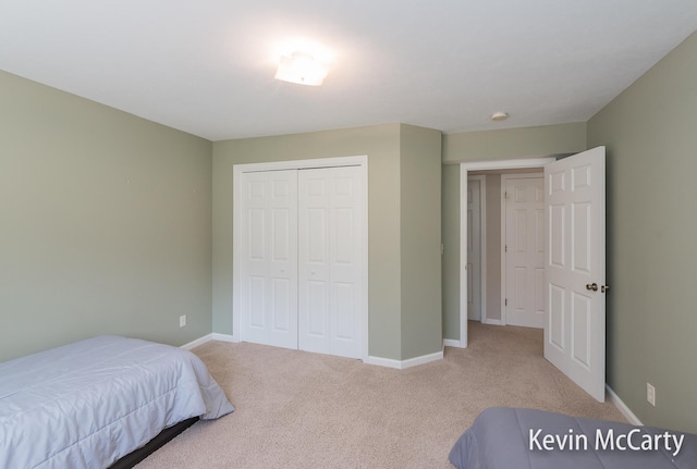 carpeted bedroom with a closet and baseboards