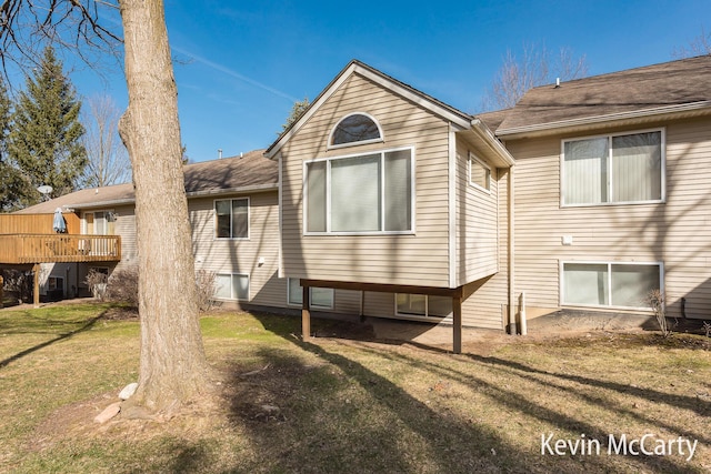 back of house featuring a lawn and a deck