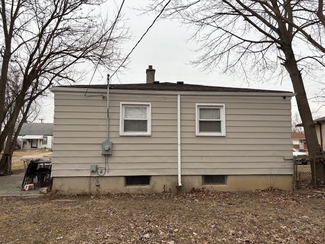 view of side of home with fence and a chimney