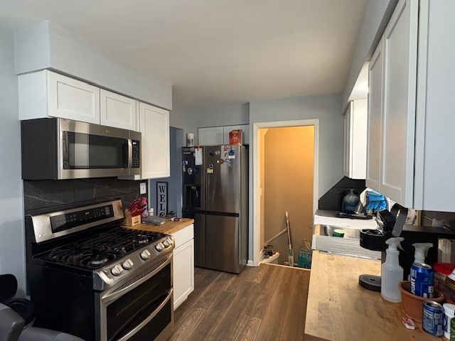 kitchen featuring stainless steel appliances, white cabinetry, dark wood-style floors, and light countertops