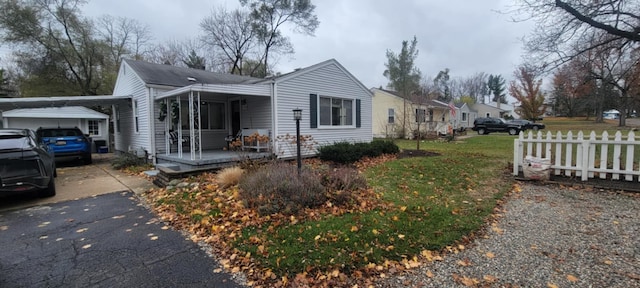 view of side of home with a porch, driveway, a yard, and fence