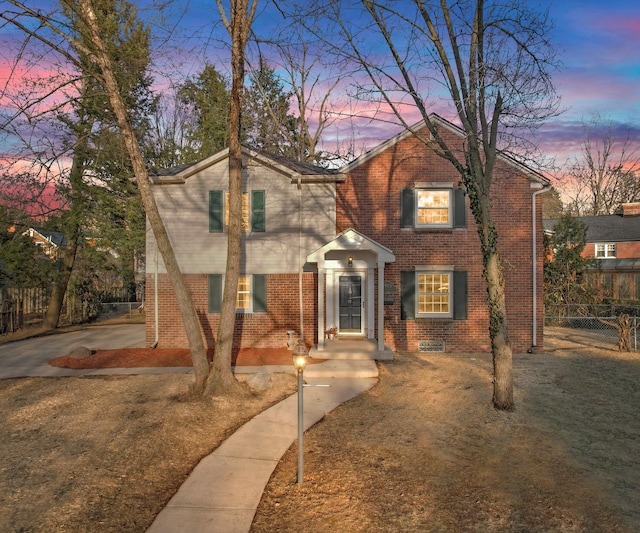 traditional home featuring brick siding and fence