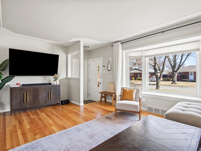 living area featuring wood finished floors, visible vents, and baseboards