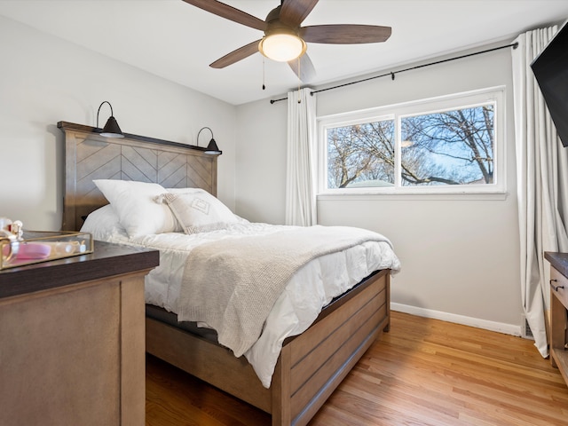 bedroom featuring baseboards, light wood-style floors, and a ceiling fan