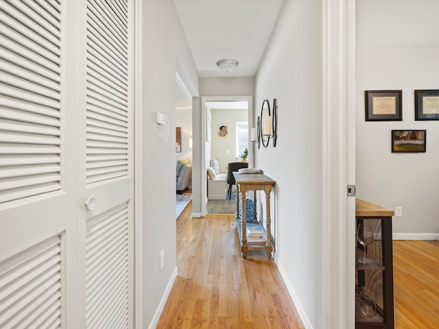 hallway featuring light wood finished floors and baseboards