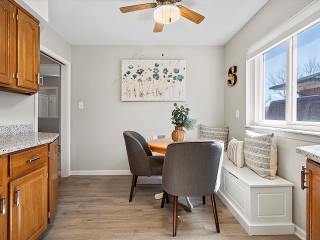 dining space featuring light wood-style flooring, baseboards, and a ceiling fan