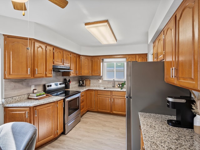 kitchen featuring under cabinet range hood, brown cabinets, stainless steel appliances, and a sink