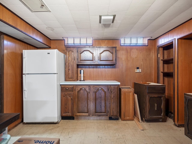 kitchen with wooden walls, light floors, light countertops, and freestanding refrigerator