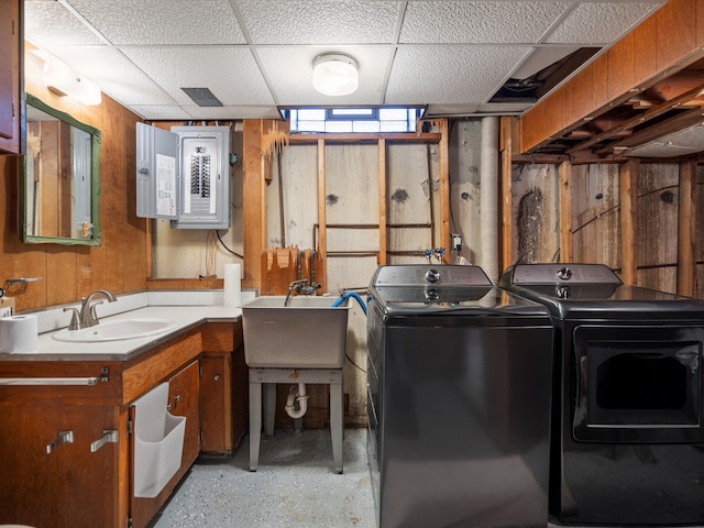 laundry room featuring a sink, electric panel, wooden walls, separate washer and dryer, and laundry area