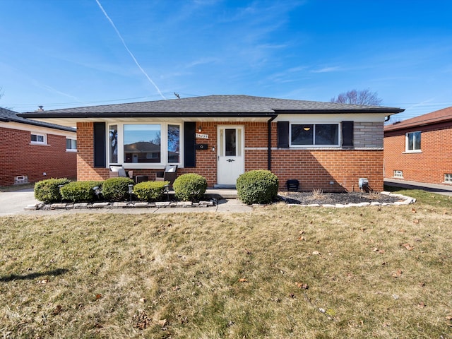 view of front of house featuring a front yard, brick siding, and a shingled roof