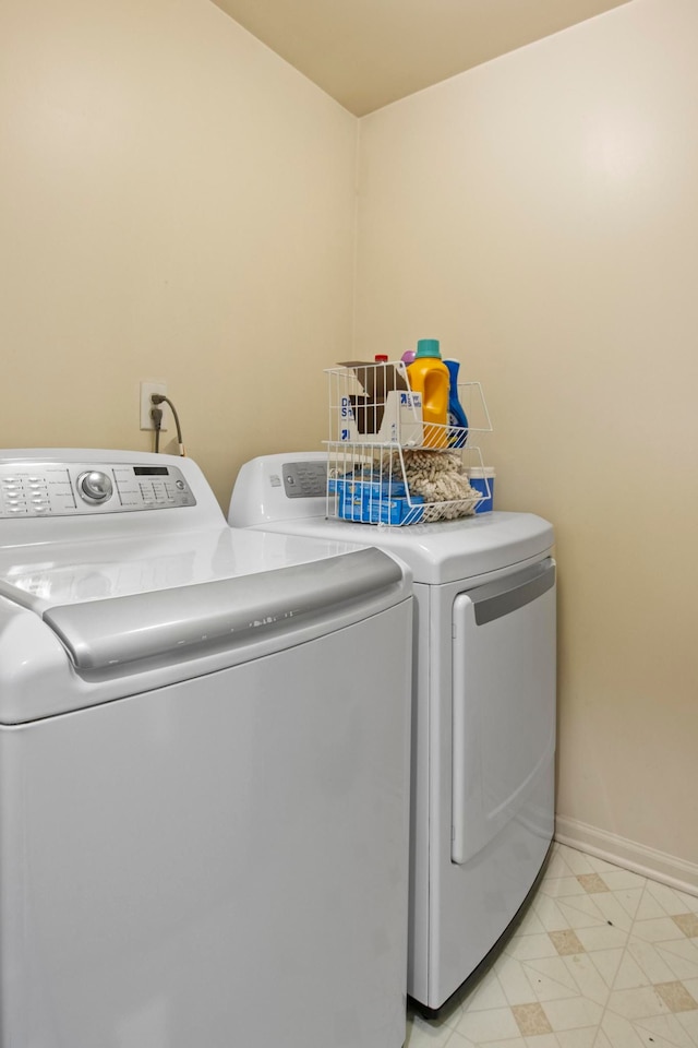 laundry room with baseboards, light floors, washing machine and dryer, and laundry area