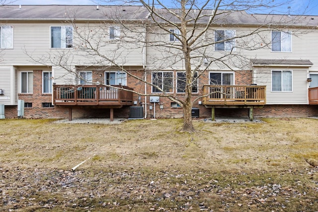 rear view of house featuring brick siding, central AC unit, and a deck