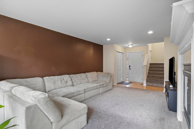 living area featuring light carpet, stairway, recessed lighting, and an accent wall