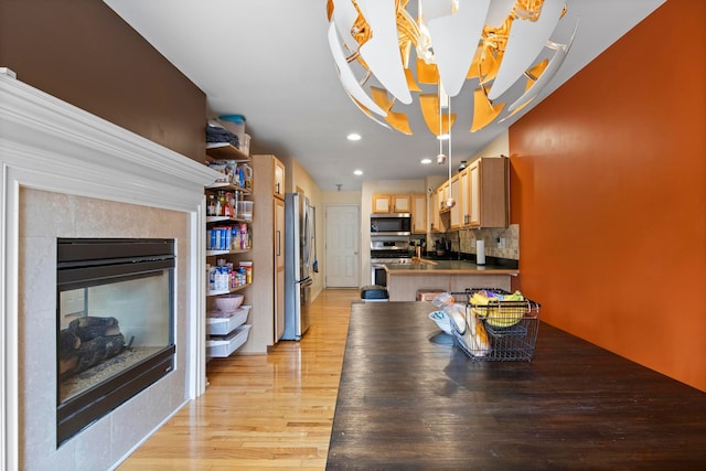 dining room featuring a fireplace, an inviting chandelier, light wood-style flooring, and recessed lighting