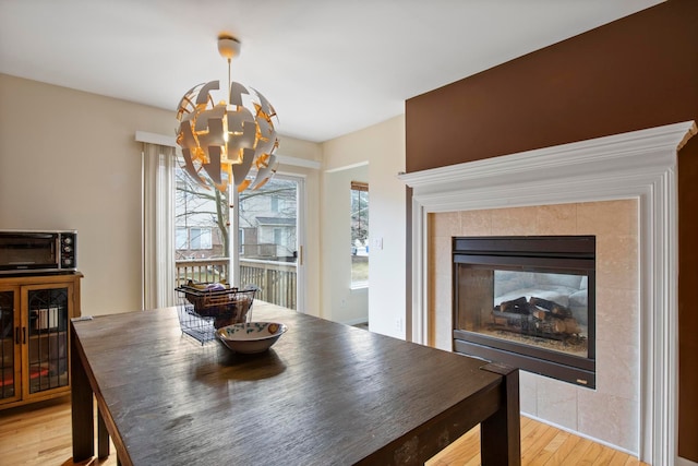 dining space with light wood-type flooring, wine cooler, a notable chandelier, and a toaster