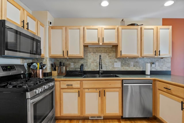 kitchen featuring visible vents, a sink, appliances with stainless steel finishes, dark countertops, and backsplash