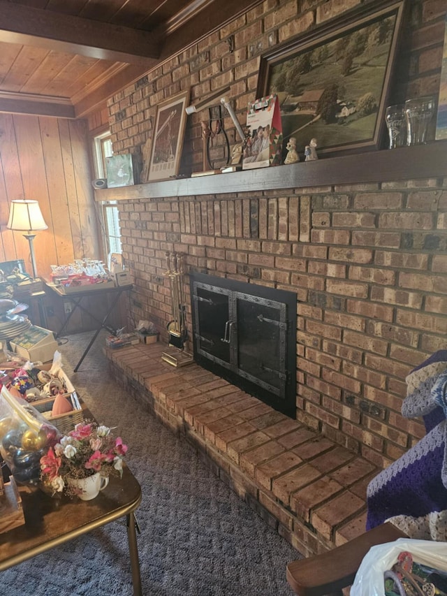 living area with beam ceiling, wooden ceiling, brick wall, wood walls, and a brick fireplace