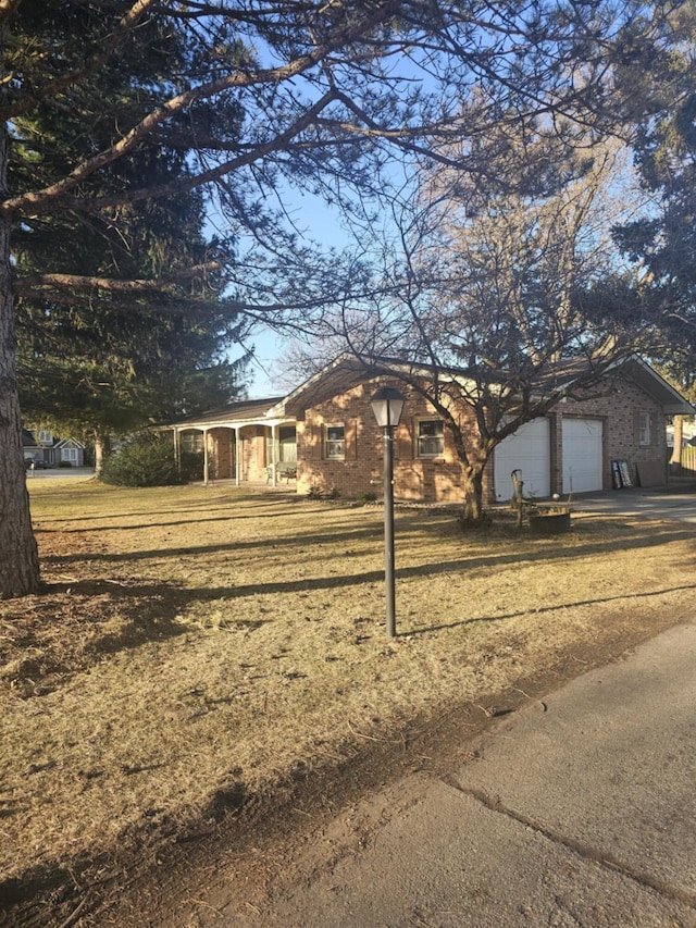 view of property exterior with a garage, brick siding, concrete driveway, and a lawn