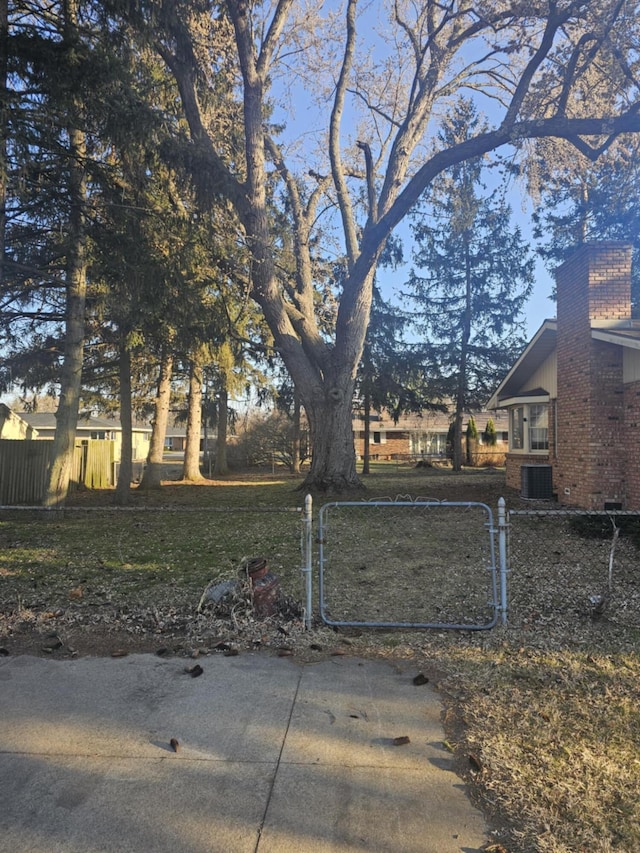 view of yard featuring a fenced front yard, central AC, and a gate