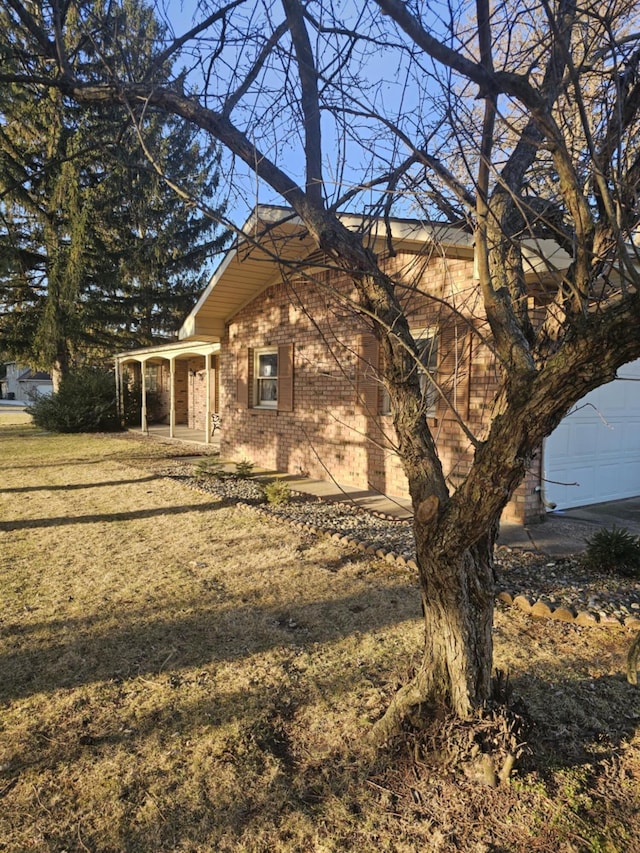 view of front facade with brick siding, a garage, and a front yard