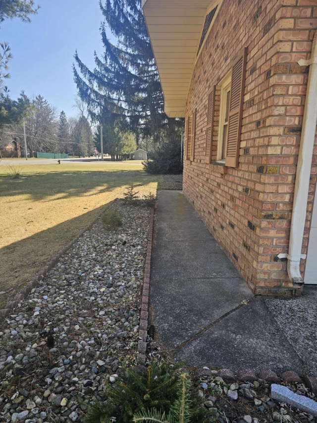 view of property exterior with a yard and brick siding