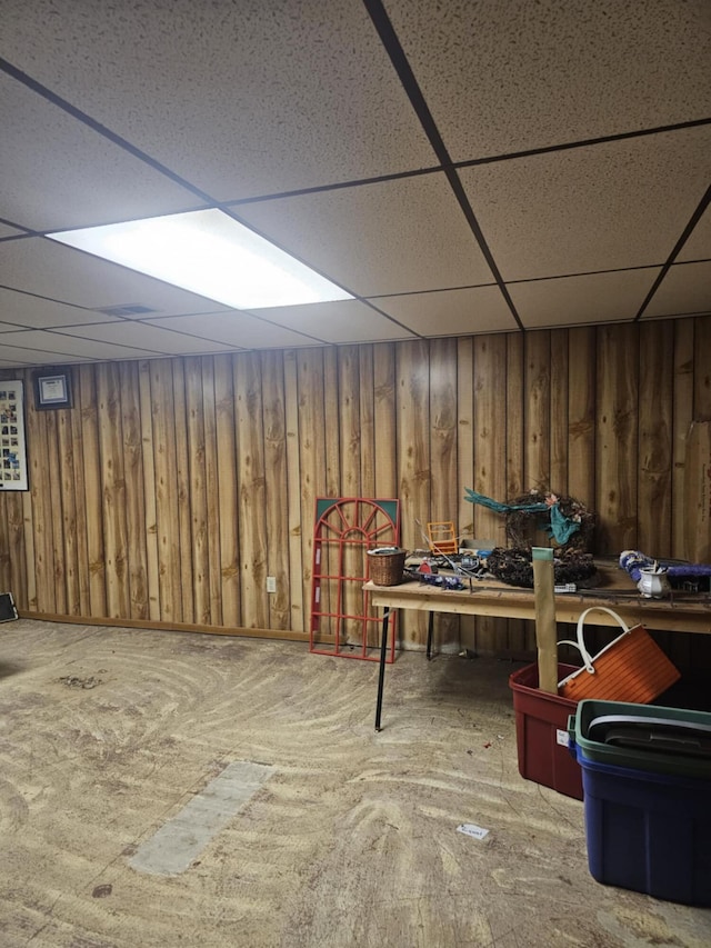 finished below grade area with a paneled ceiling and wood walls