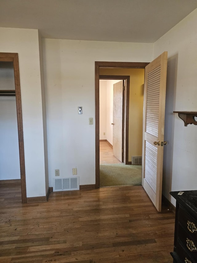 unfurnished bedroom with visible vents, baseboards, and dark wood-style floors