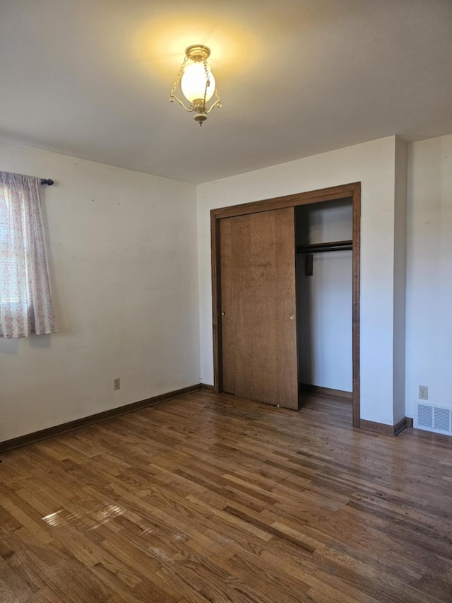 unfurnished bedroom featuring a closet, baseboards, visible vents, and dark wood-style flooring