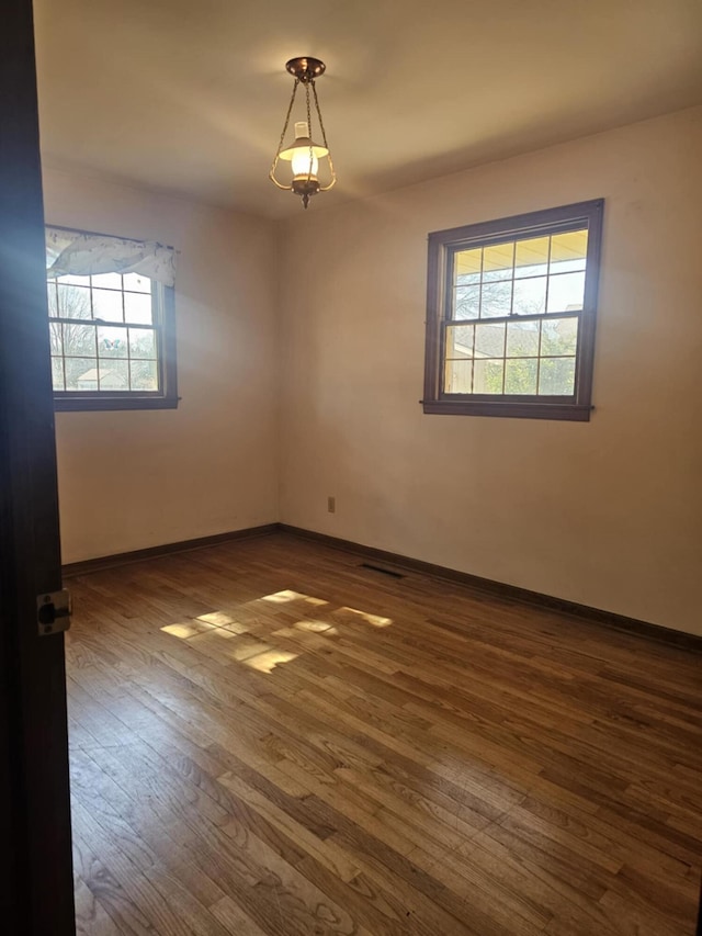 empty room featuring baseboards and dark wood-style flooring