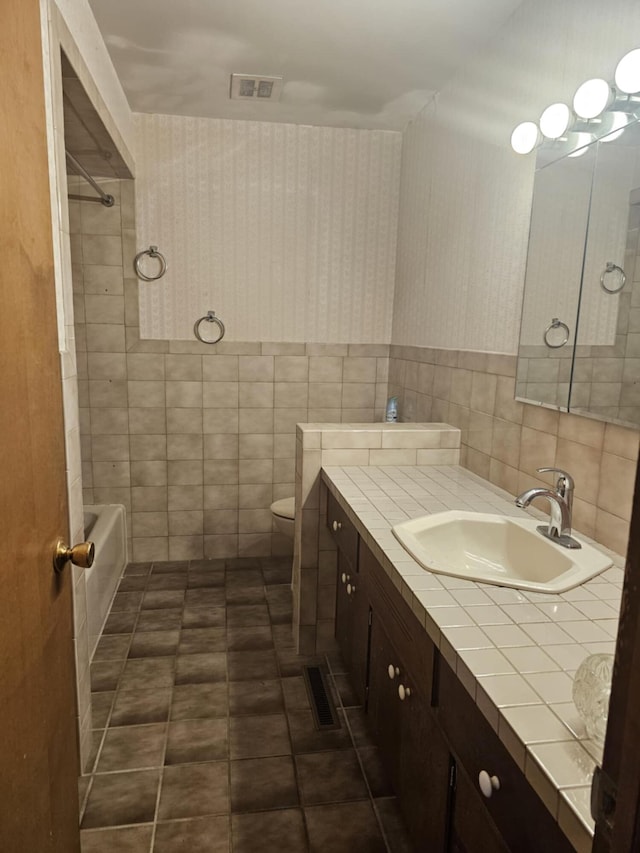 full bath featuring visible vents, wallpapered walls, tile walls, tile patterned flooring, and vanity