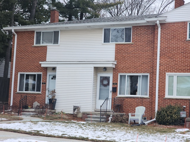 view of front facade with brick siding and a chimney