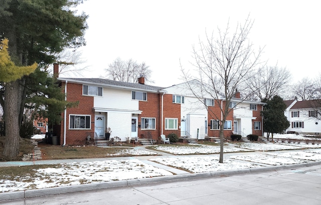 multi unit property with a residential view, brick siding, a chimney, and entry steps