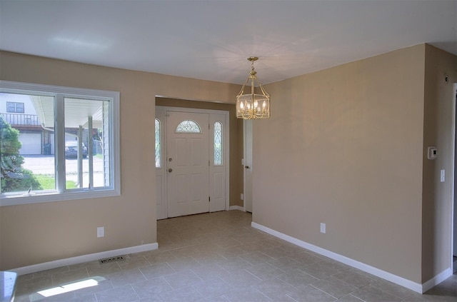 foyer entrance with visible vents, baseboards, and a chandelier