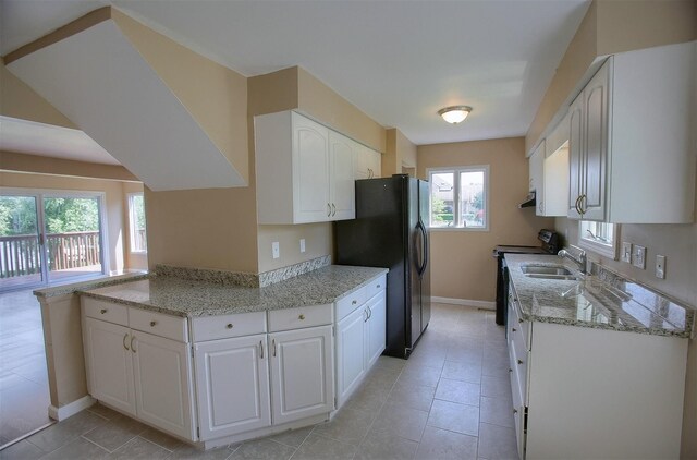 kitchen featuring a sink, white cabinetry, range with electric stovetop, and freestanding refrigerator