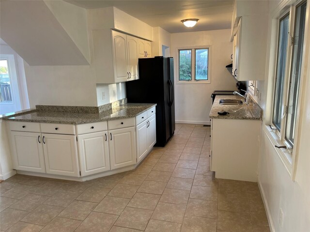 kitchen featuring white cabinets, baseboards, freestanding refrigerator, and a sink