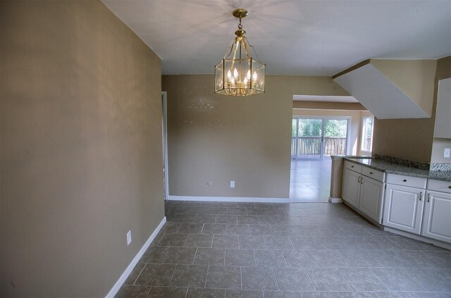 unfurnished dining area with an inviting chandelier and baseboards