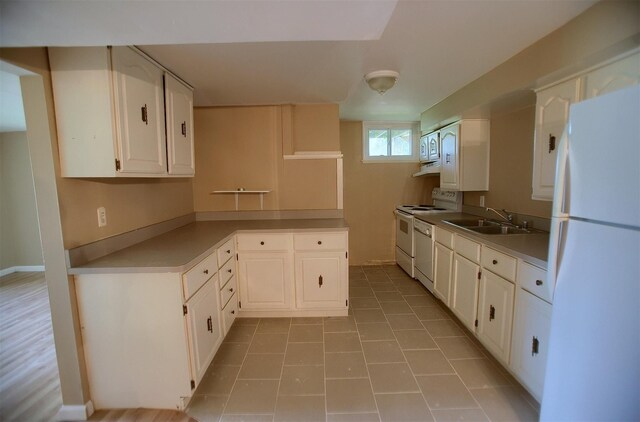 kitchen with white appliances, a peninsula, a sink, white cabinets, and under cabinet range hood