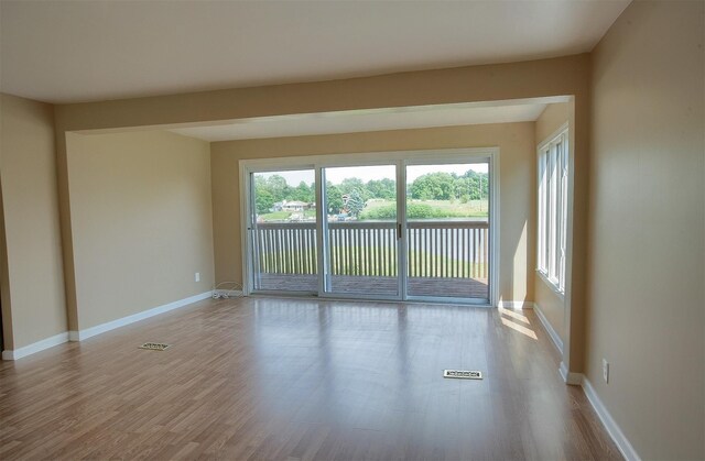 spare room featuring baseboards and wood finished floors