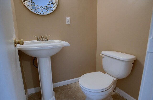 bathroom featuring tile patterned flooring, toilet, baseboards, and a sink